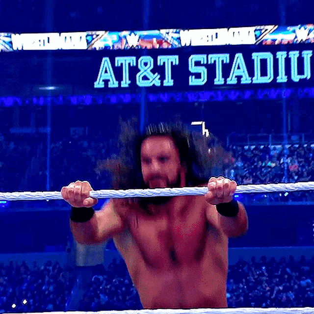 a man in a wrestling ring with a sign that says at & t stadium