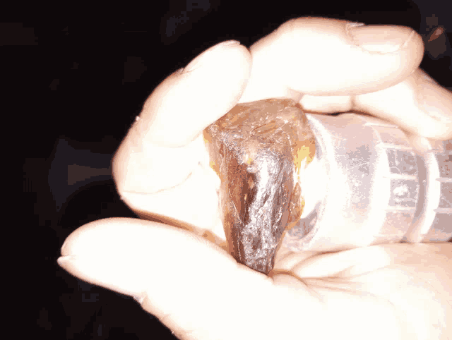 a close up of a person 's hand holding a rock