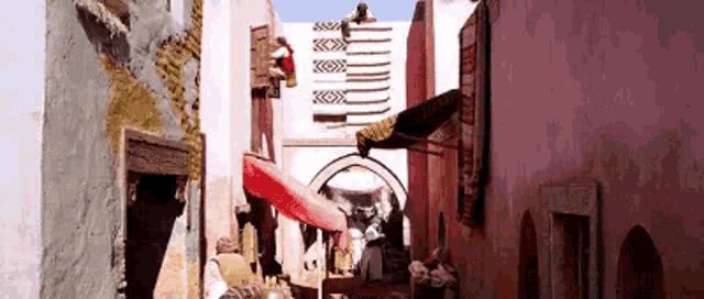 a narrow alleyway between two buildings with a red awning and a flag on the wall .