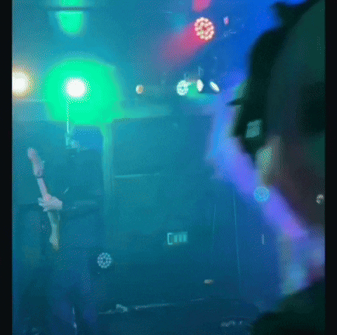a man playing a guitar in a dark room with a sign that says exit on it