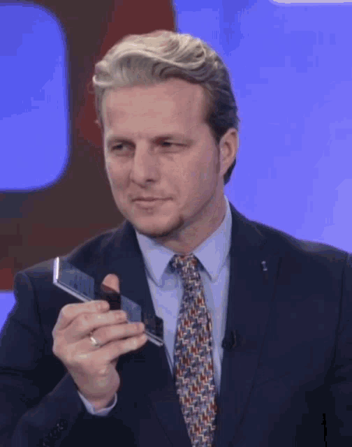 a man in a suit and tie is holding a small object