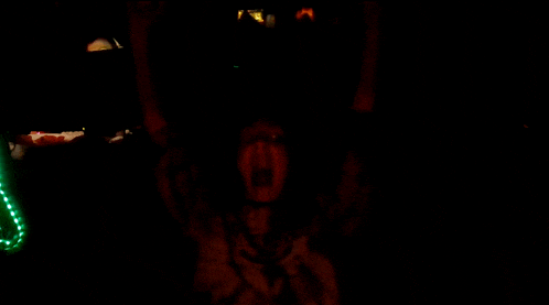 a person is screaming in the dark with green lights behind them