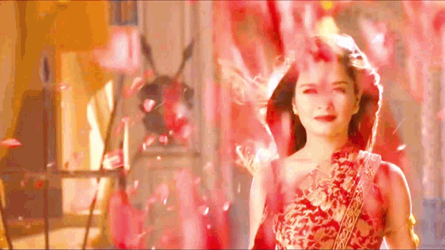 a woman in a red dress is surrounded by red petals ..
