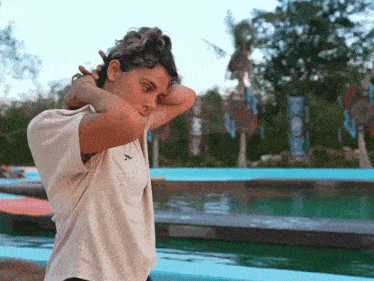 a woman wearing a t-shirt that says bc is standing near a pool