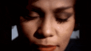 it is a close up of a woman 's face with her eyes closed .