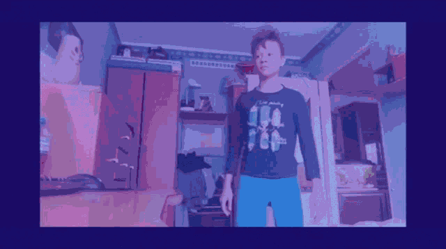 a boy wearing a minecraft shirt is dancing in a living room