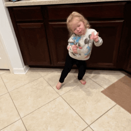 a little girl wearing a minnie mouse sweater giving a thumbs up