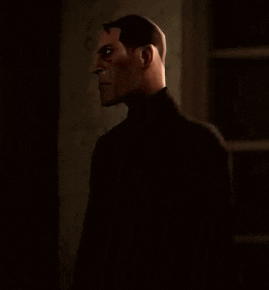 a man in a black suit is standing in the dark and looking at the camera .