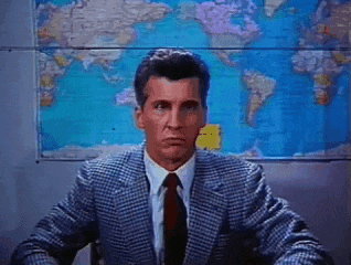a man in a suit and tie is sitting in front of a world map .