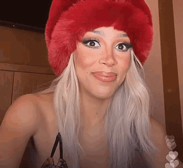 a woman wearing a red fur hat is smiling .
