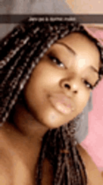 a woman with braids is taking a selfie and smiling .