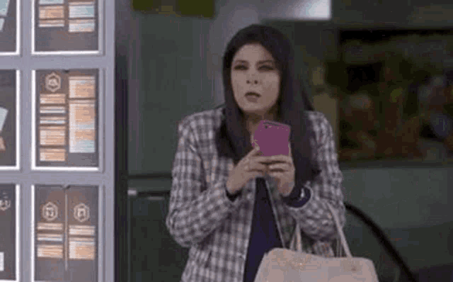 a woman is holding a pink cell phone in her hand .