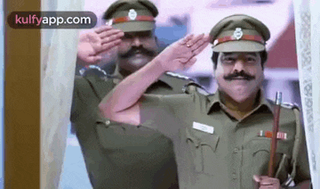 two police officers are saluting in front of a building .