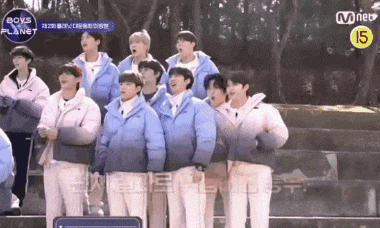 a group of boys in blue jackets are standing next to each other on a bench .