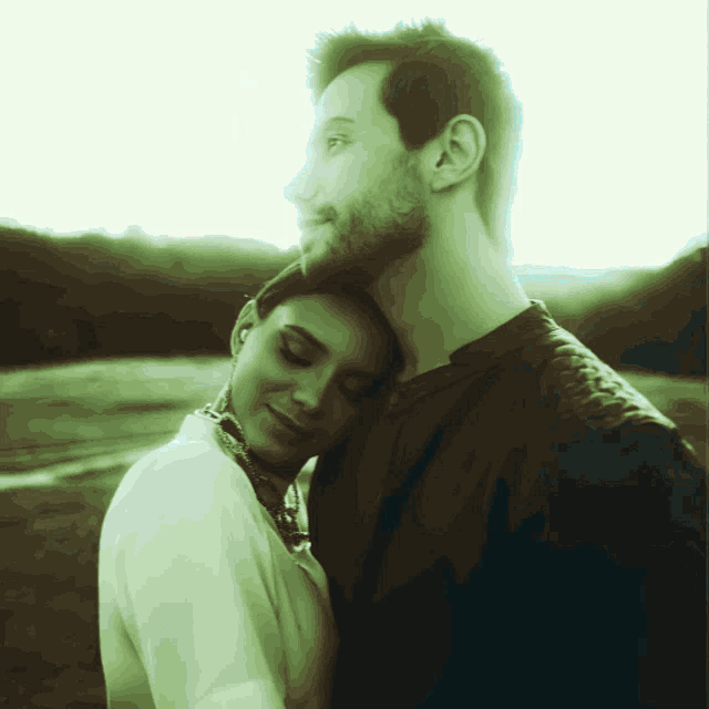 a man and a woman are hugging each other with the woman 's head on the man 's shoulder