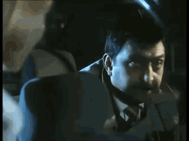 a man is holding a gun in his mouth in a dark room .