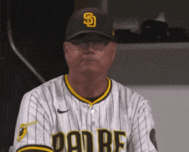 a man wearing a padres jersey and hat looks at the camera