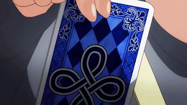 a person is holding a blue playing card with a celtic knot design