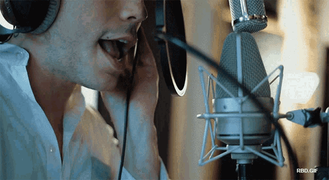 a man wearing headphones singing into a microphone with rbd.gif written below him