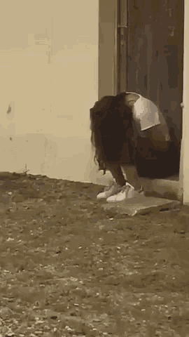 a woman is squatting down in front of a door .