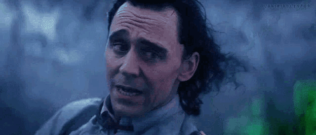 a close up of a man 's face with his hair blowing in the wind in a dark room .