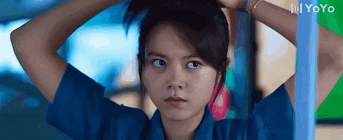a girl in a blue shirt has her hair in a ponytail and the word yoyo is on the bottom right