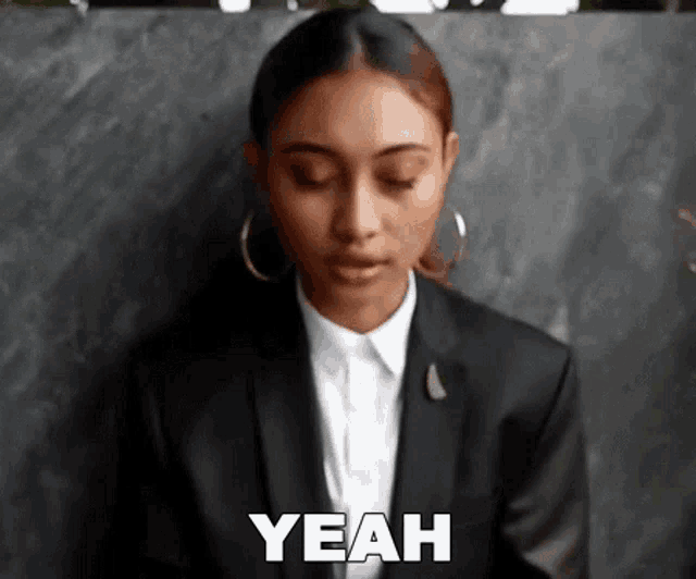 a woman in a suit is saying yeah