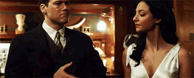 a man in a suit and tie is standing next to a woman in a white dress in a room .