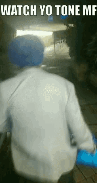 a man in a blue hat is walking down a street with the words watch yo tone me