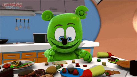a gummy bear is sitting at a table with a bunch of food and the words gummy bears & friends above him