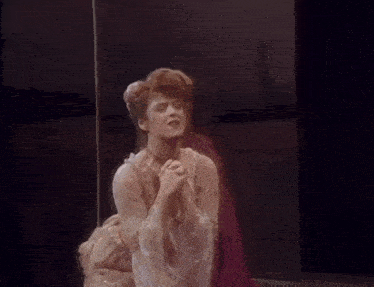 a woman in a white dress is singing into a microphone on a stage