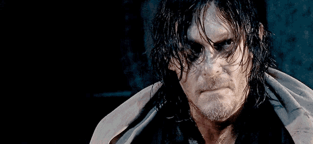 a man with wet hair and a beard looks at the camera with a serious look on his face