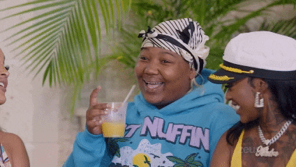 a woman wearing a blue hoodie that says ' nuffin ' on it is drinking orange juice