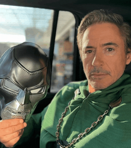 a man in a green sweatshirt is holding a helmet