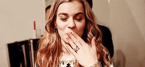 a woman with long hair is blowing a kiss with her hand .