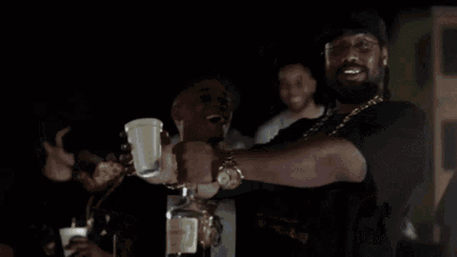 a man in a black shirt is holding a cup and laughing