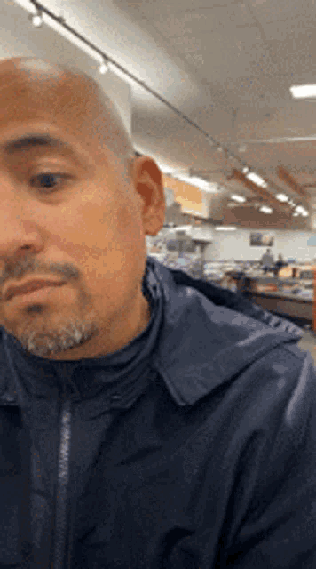 a bald man with a beard is standing in a store