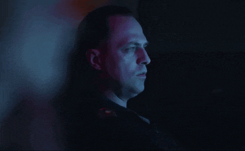 a man is standing in a dark room with blue lights behind him
