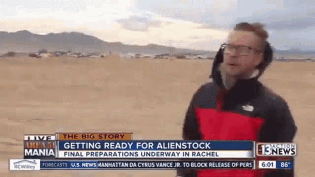 a man in a red and black jacket stands in front of a headline that says " the big story "