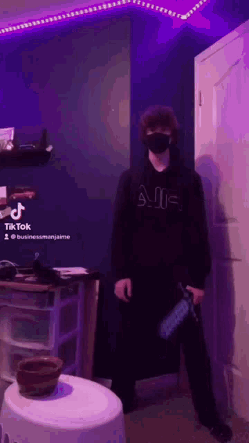 a man wearing a black mask is standing in a room holding a sword .