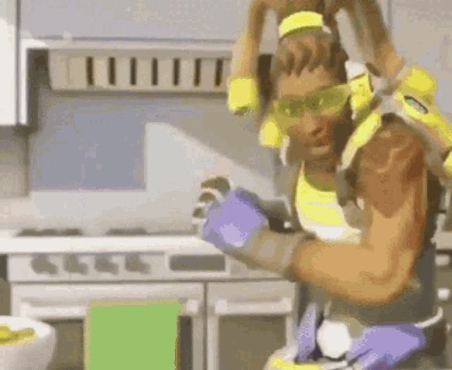 a man in a yellow and purple outfit is standing in a kitchen with a green towel .