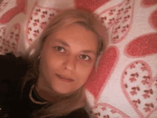 a woman in a black shirt is laying on a bed with hearts on it