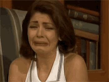 a woman is crying in front of a bookshelf with books .