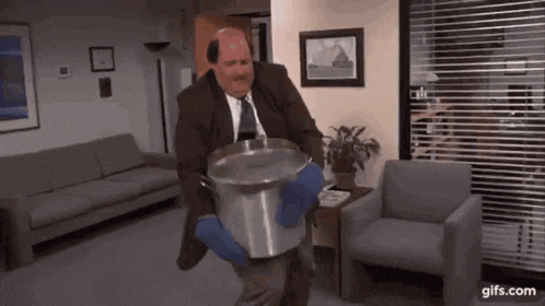 a man in a suit and tie is carrying a large pot of water .