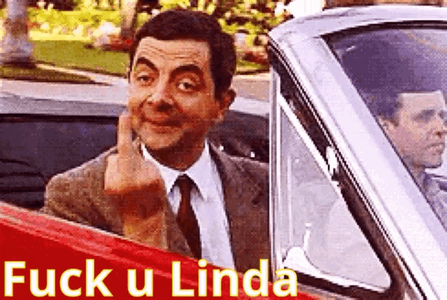 a man in a suit and tie is giving the middle finger in a car