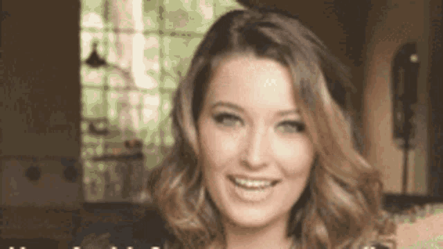 a woman is smiling and looking at the camera in a room .