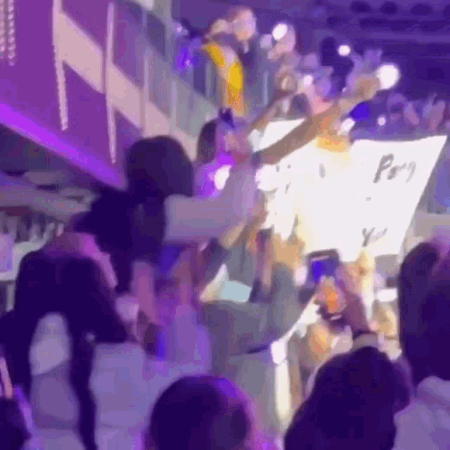 a crowd of people are standing in a stadium holding a sign that says pray you .