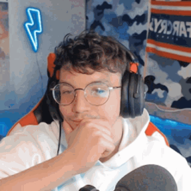 a young man wearing headphones and glasses is sitting in front of a lightning bolt sign
