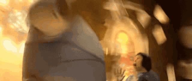a blurry picture of two people standing next to each other in front of a fire .
