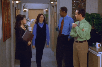 a group of people are standing in a hallway and one of them is wearing a green shirt